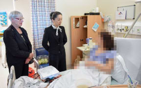 Mayor Steve Chadwick, Chinese Ambassador to New Zealand Wu Xi visit one of the patients in Rotorua Hospital.