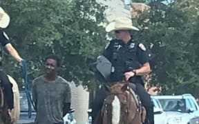 blacTexas police have apologised after an image of two white officers on horseback leading a handcuffed k man by a rope caused an outcry online.