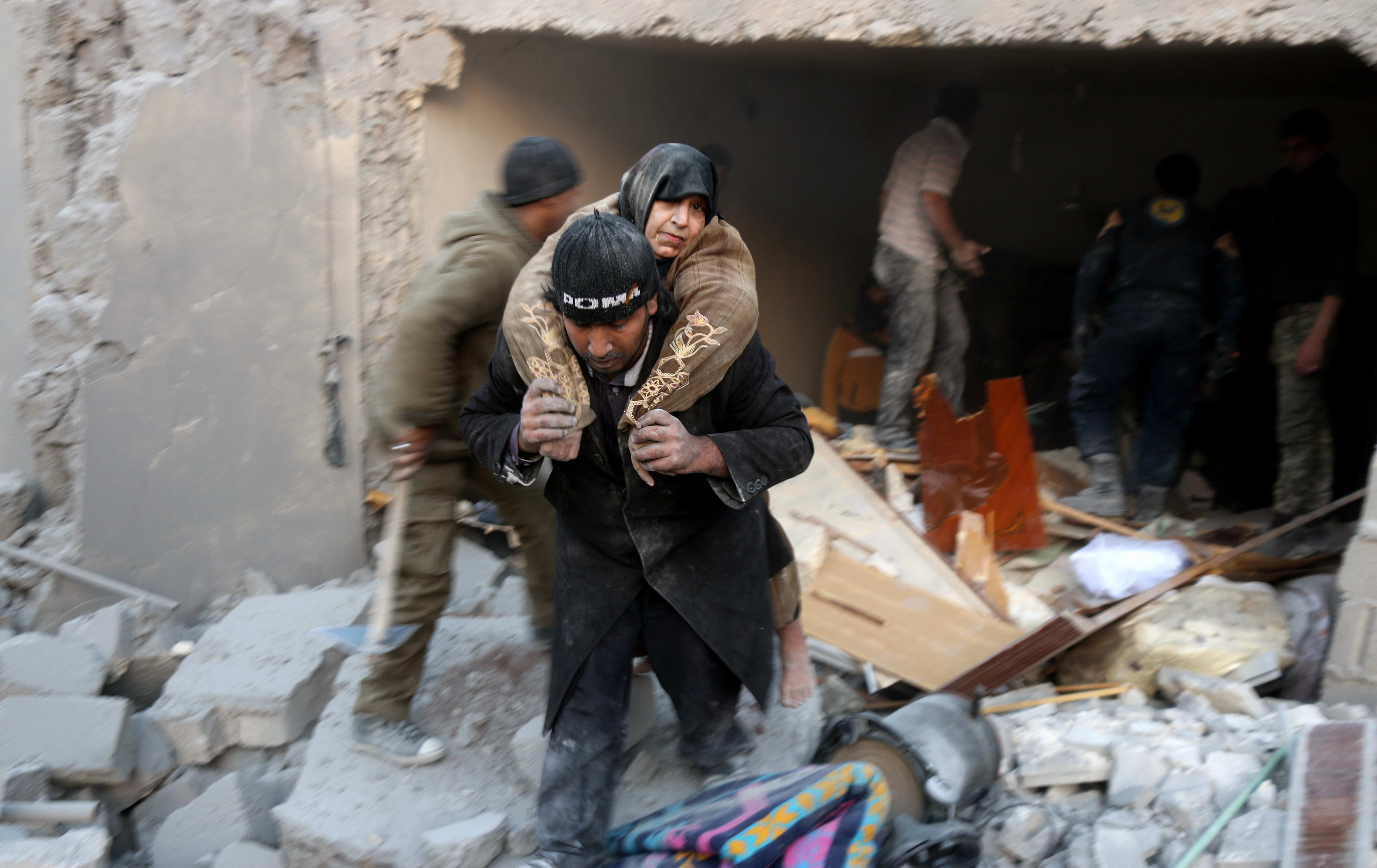 A rescuer carries a woman from the rubble of a building in Aleppo's rebel-held district of al-Hamra on 20 November.