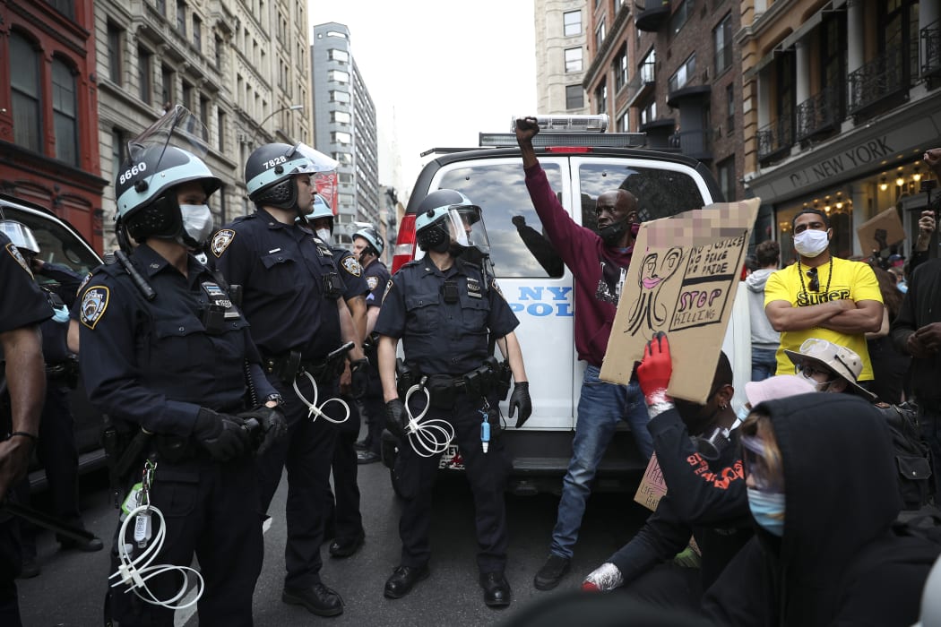 Protesters demand to kneel down from police officers with the call for unity during a protest in New York