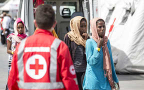 Women rescued off the coast of Libya wait to be processed by authorities after arriving at the port of Palermo, Sicily on 24 August.