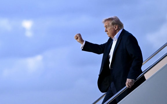 US President Donald Trump raises a fist as he steps off Air Force One at Palm Beach International Airport in West Palm Beach, Florida, on April 11, 2025. Trump is heading to Palm Beach to spend the weekend at his Mar-a-Lago resort. (Photo by Mandel NGAN / AFP)