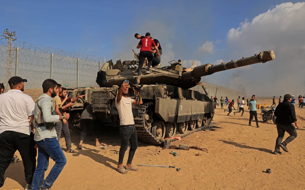 Palestinians take control of an Israeli tank after crossing the border fence with Israel from Khan Yunis in the southern Gaza Strip.