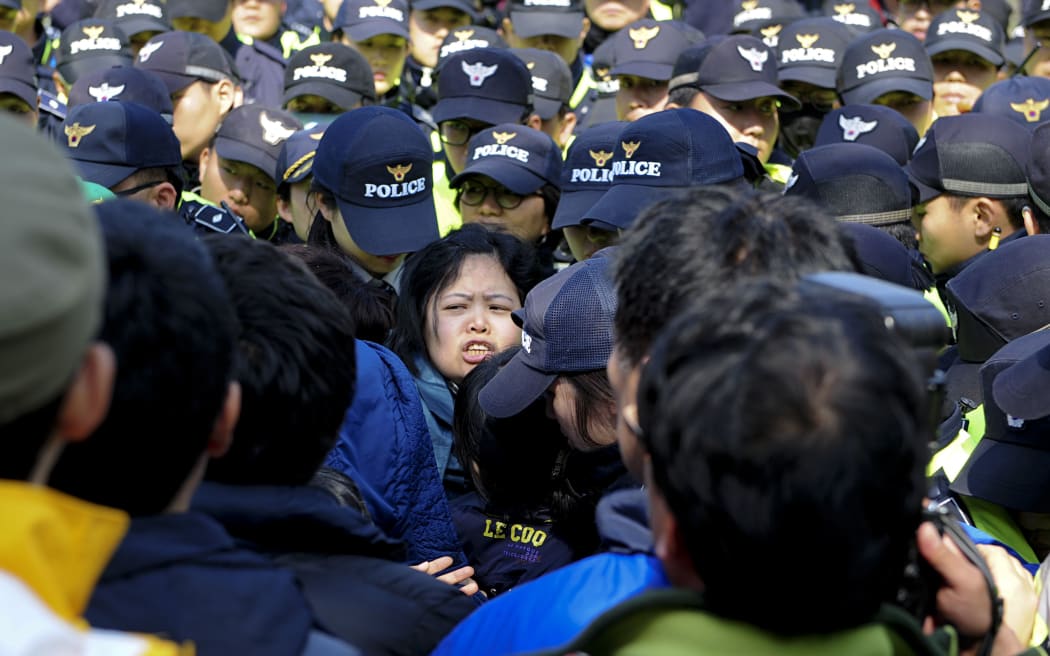 Relatives of missing passengers struggle with police officers while trying to protest the government's rescue operation.