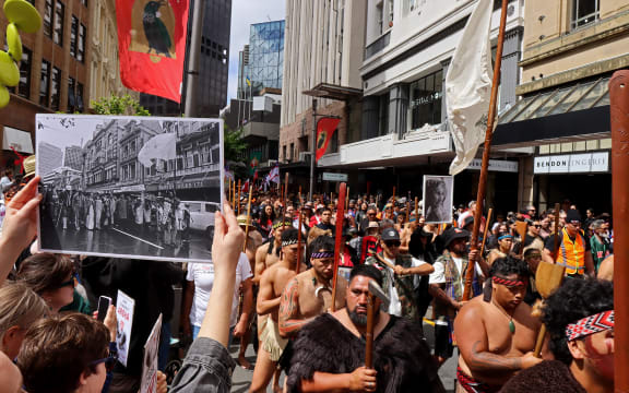 John Miller's photograph of the 1975 land march held up in the same location at the 2024 Hīkoi in Pōneke Wellington