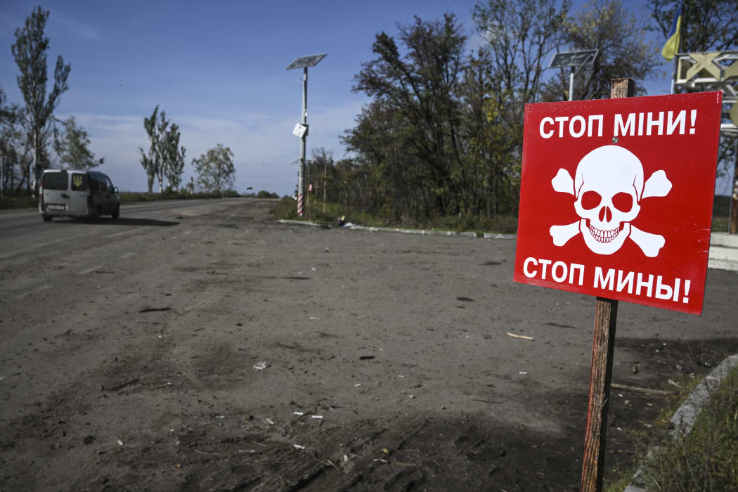 This photograph taken in Izyum, eastern Ukraine on September 29, 2022, shows a landmine warning sign next to a road, amid the Russian invasion of Ukraine. (Photo by Juan BARRETO / AFP)