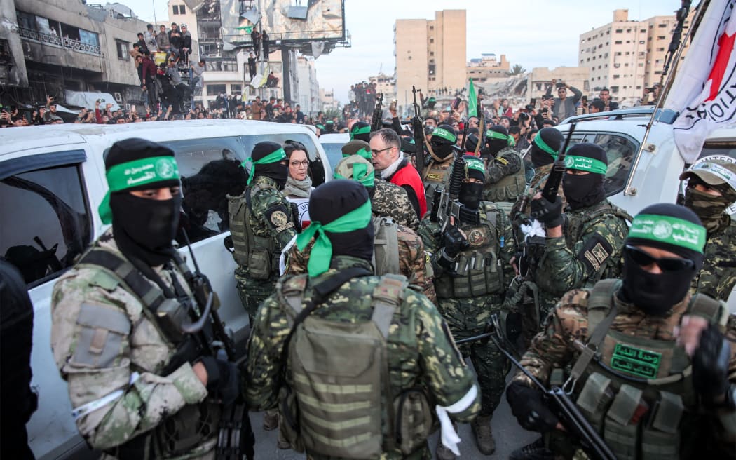 Members of the International Committee of the Red Cross (ICRC) speak with fighters of the Ezzedine al-Qassam Brigades, Hamas's armed wing, in Saraya Square in western Gaza City on January 19, 2025. The Israeli military said the Red Cross had confirmed the handover of three hostages on January 19, the first to be released as part of a ceasefire deal with Hamas. The Hostage and Missing Families Forum campaign group had identified the three women set to be released as Emily Damari, Romi Gonen and Doron Steinbrecher, seized during Hamas's October 7, 2023 attack that triggered the war. (Photo by Omar AL-QATTAA / AFP)