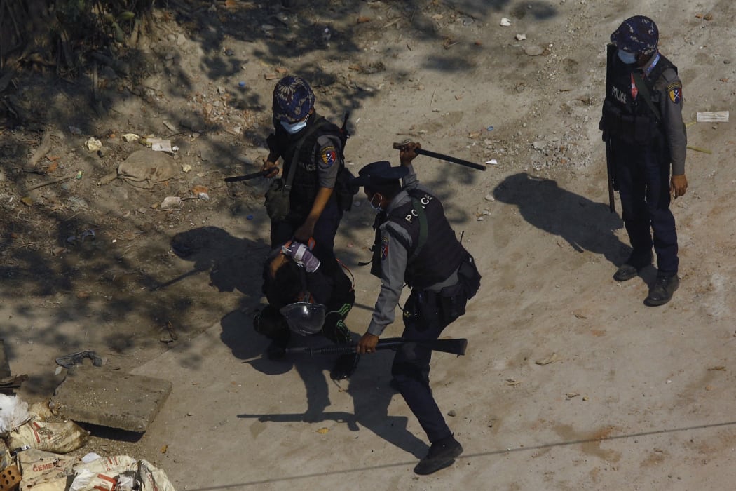Police beat a protester as they detain him during a demonstration against the military coup in Yangon on 6 March, 2021.