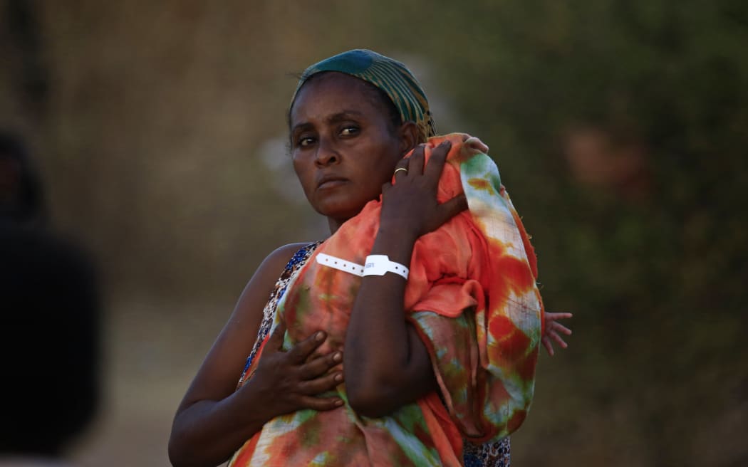 An Ethiopian refugee who fled fighting in Tigray province carries her baby as she walks at the Um Rakuba camp in Sudan's eastern Gedaref province, on November 21, 2020.
