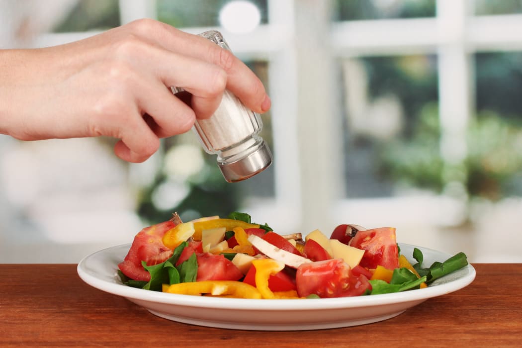 16738591 - hand adding salt using  salt shaker on bright background