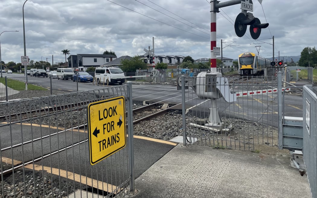 A train comes through a level crossing in Takanini