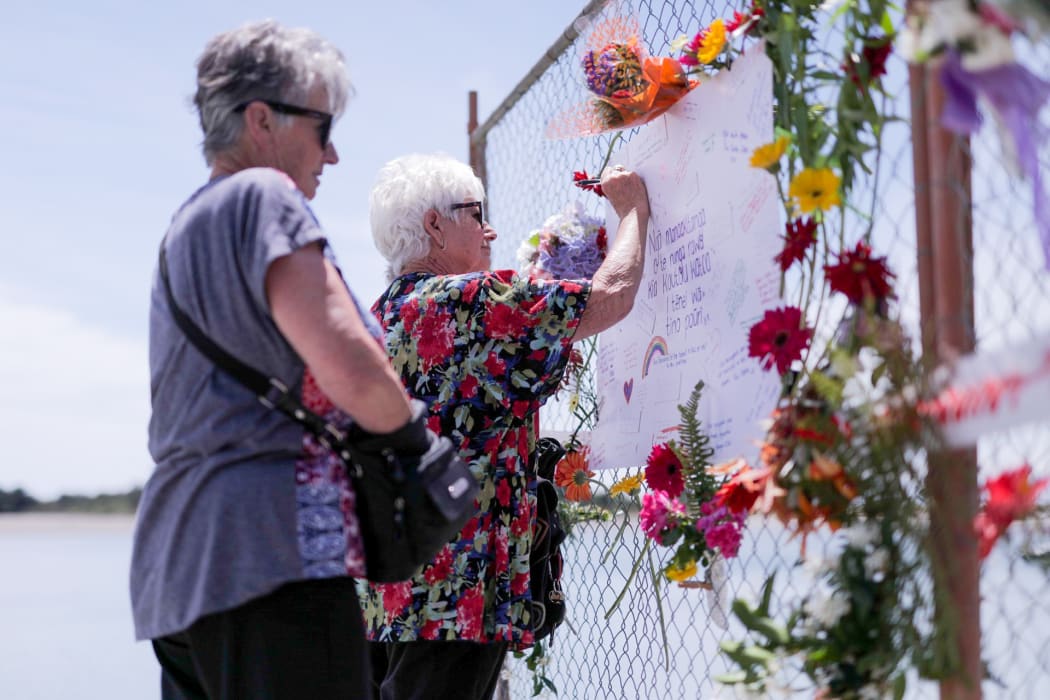 A woman writing a message on the cordon fence that's serving as a makeshift memorial.