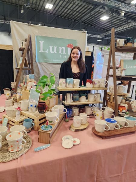Luni Pottery's Sam Peterson stands at a market stall with her handmade mugs.