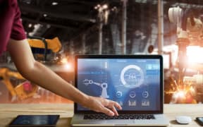 Engineer touching laptop check and control welding robotics automatic arms machine in intelligent factory automotive industrial with monitoring system software.