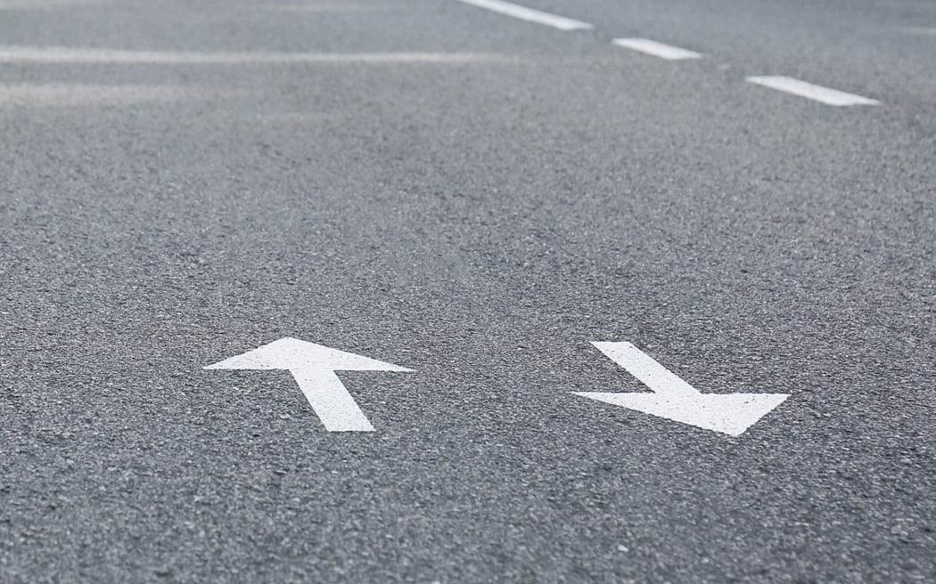Arrow signs on asphalt road showing direction of movement
