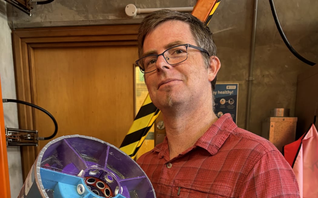 Doctor Andrew Hall holding an acoustic metamaterial system, designed to allow airflow into homes while keeping loud noise out