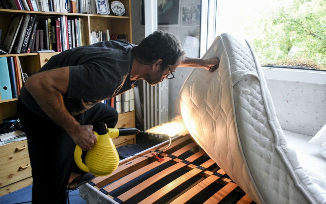 A man steam sprays under a mattress to eliminate bedbugs in Paris, France, on 8 October, 2023.