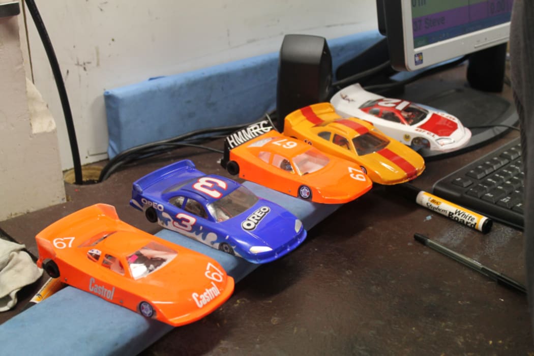 An image of a range of different slot cars made by club members sitting on a workbench.