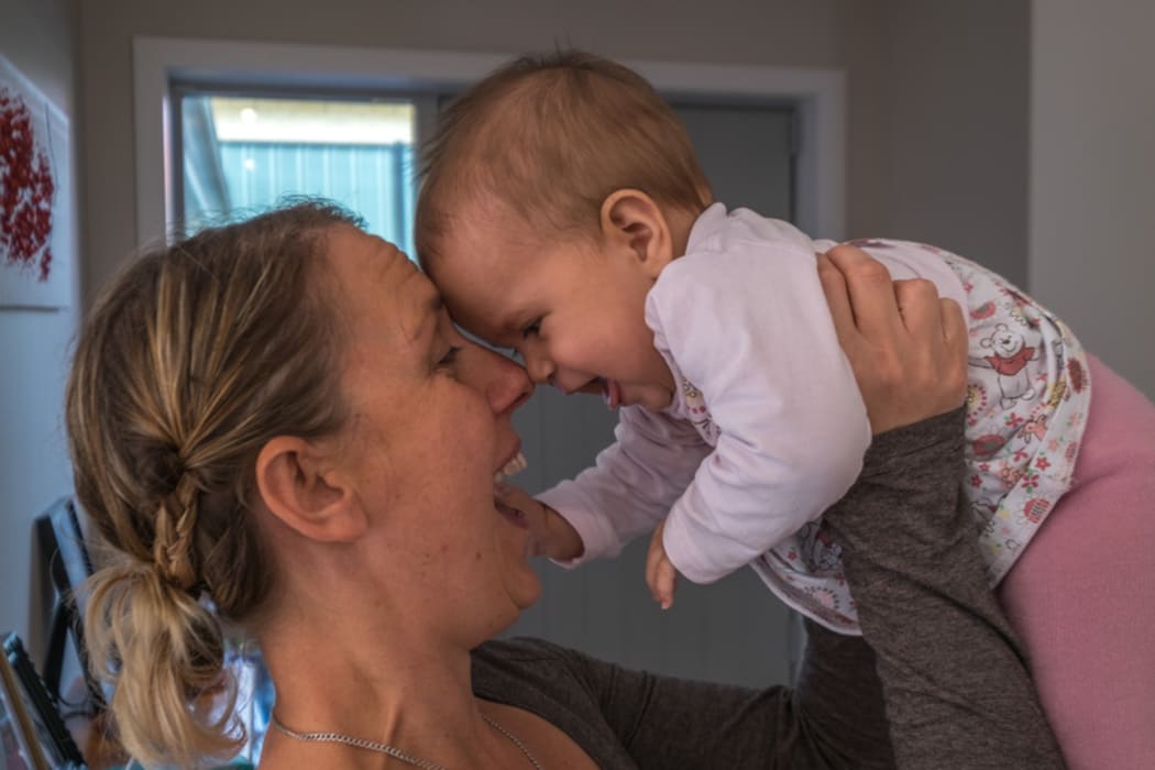 Calli Cleland holds up one of her twins, and one of four children to her deceased husband Daniel Kopa, who was recently killed after being struck by a car on Hobson Street.
