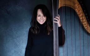 Jazz harpist Amanda Whiting stands next to her harp.