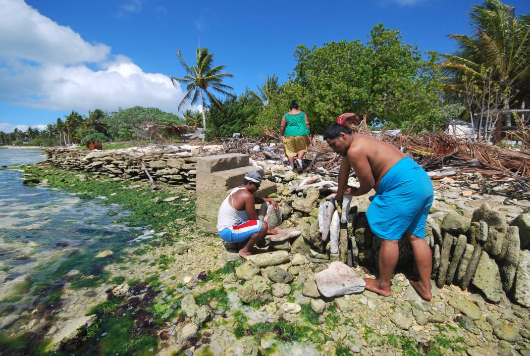 People of Kiritimati coral atoll building a stone seawall to struggle against sea level rise cause by global warming.