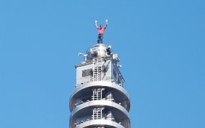 US rock climber Alex Honnold raises his arms from the top of the Taipei 101 building after he successfully free soloed the landmark skyscraper without ropes or safety gear in Taipei on January 25, 2026. (Photo by I-HWA CHENG / AFP)