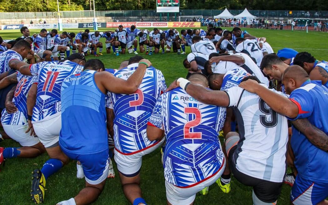 The Fiji and Samoa teams pray after their Pacific Nations Cup title decider.