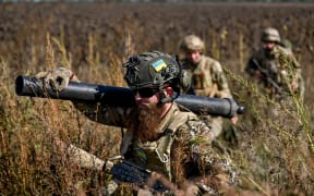 Military mortar crew march through a field of dry sunflowers, Zaporizhzhia Region, southeastern Ukraine.