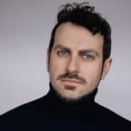 Alfredo looks into the camera. He is wearing a black turtleneck.
