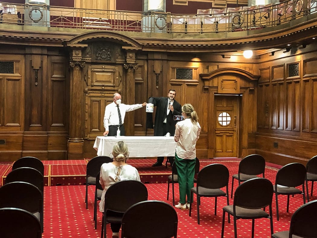 The Speaker and the Clerk of the House perform an online random biscuit tin ballot for a Youth Parliament bill in the old Legislative Chamber.