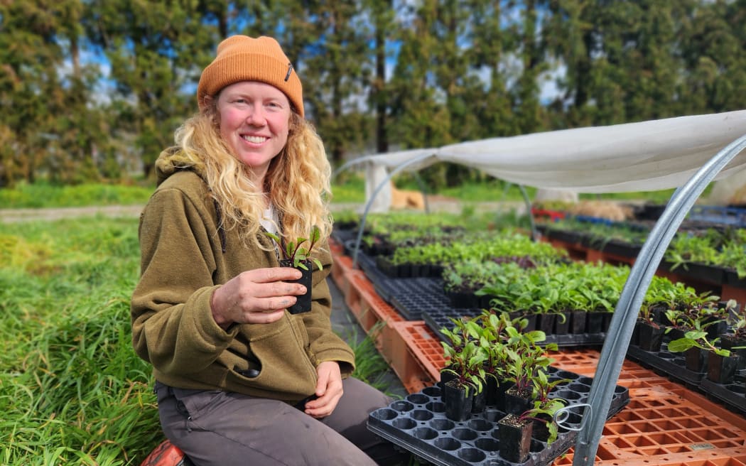 Jemma Ostenfeld kneeling in front of punnets and holding one of her seedlings