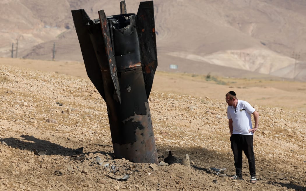 A man checks a fallen rocket half-buried in the ground on the outskirts of Jericho on June 8, 2026, following Iranian and Iran-backed Houthi rebel attacks. Israel and Iran traded fire on June 8, seriously testing a fragile truce and threating hopes for a deal to end the Middle East war.