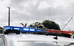 A police car at Hillsborough, Auckland,  after a person in possession of a firearm was shot and wounded by police following a chase that ended on Lilac Grove.