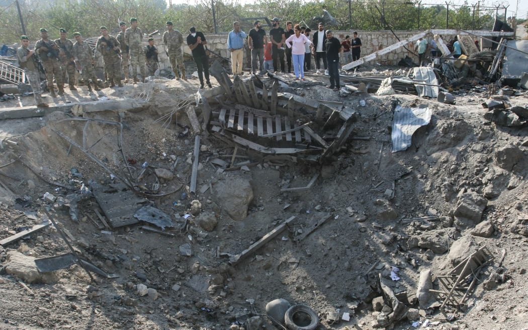 Lebanese soldiers and local residents stand at the site of an Israeli airstrike in the southern Lebanese village of Toura on 6 November, 2025.