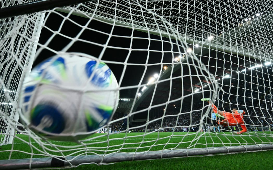 Tottenham Hotspur's Italian goalkeeper Guglielmo Vicario dives the wrong way as PSG successfully score a penalty during the penalty shootout at the end of the 2025 UEFA Super Cup final.