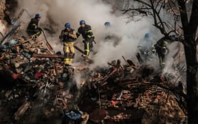 Ukrainian firefighters work on a destroyed building after a drone attack in Kyiv on 17 October 2022, amid the Russian invasion of Ukraine.