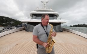 Captain Aaron Clark serenades Opua from Artefact’s foredeck.