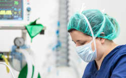 Covid-19 outbreak. Healthcare worker. Nurse working in intensive care unit. Mechanical ventilation system in the background .