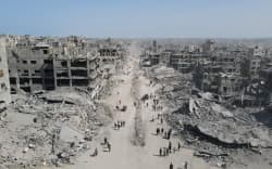 In this aerial view, People walk amid the destruction in Gaza City in the northern Gaza Strip on October 11, 2025, a day after a ceasefire took effect. Israel declared a ceasefire in Gaza and began to pull back its forces on October 10, as tens of thousands of exhausted Palestinians made their way back to their devastated homes. (Photo by AFP)
