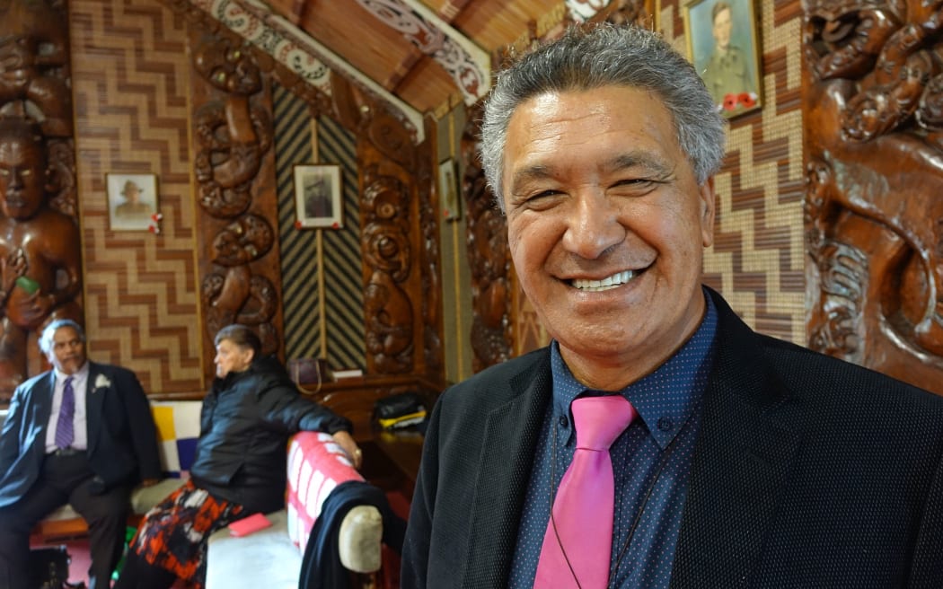 Man faces camera smiling inside marae