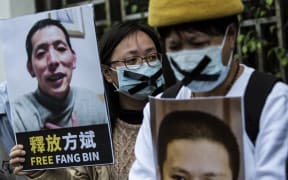 A pro-democracy activist for the HK Alliance holds a placard with an image of citizen journalist Fang Bin, as she protests outside the Chinese liaison office in Hong Kong on 19 February, 2020, in protest against Beijing’s detention of prominent anti-corruption activist Xu Zhiyong.