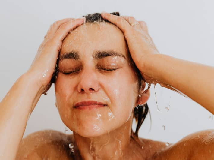 A woman washes her hair in the shower