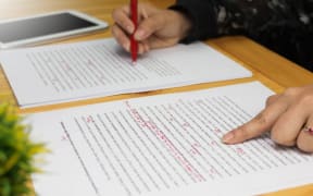 hand working on paper for proofreading. marking paper. grading paper.