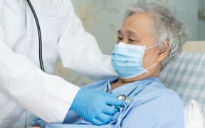 A patient wearing a face mask being checked on by a doctor in hospital, during the Covid-19 pandemic.