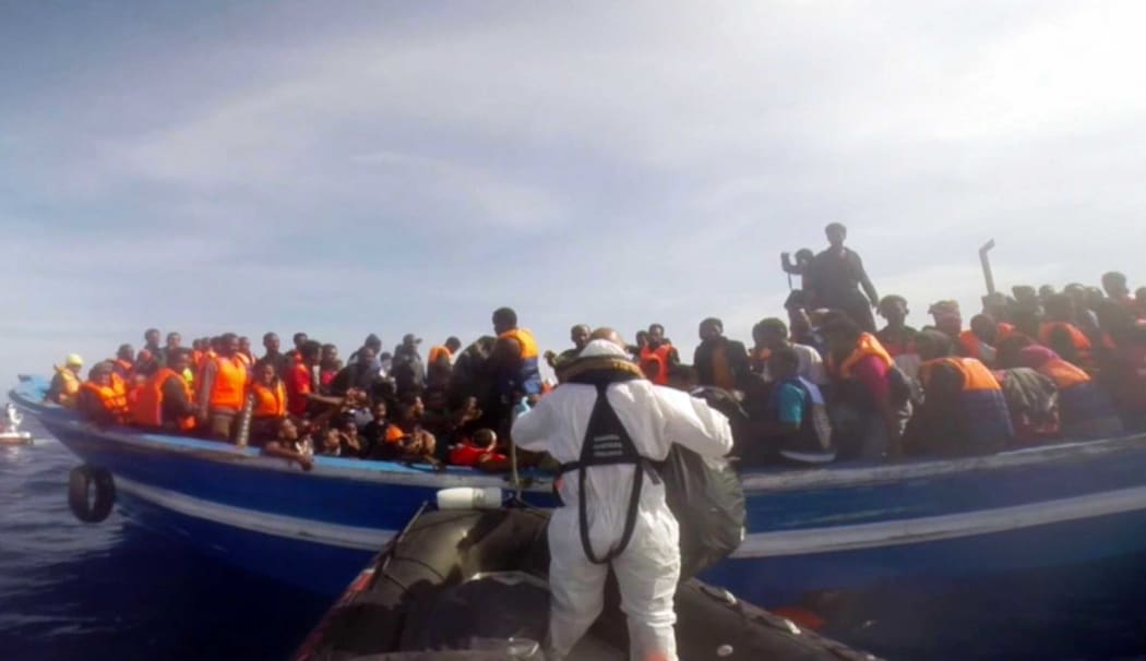 This image grab made from a handout video released by the Italian Coast Guard (Guardia Costiera) on May 3, 2015, shows an Italian coast guard taking part in a rescue operation of a boat carrying 397 migrants, on May 2, 2015, in the Mediterranean Sea.