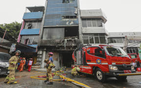 Firefighters are seen at the scene where they have extinguished a fire that killed at least 22 people at a seven-storey building in central Jakarta on 9 December, 2025.