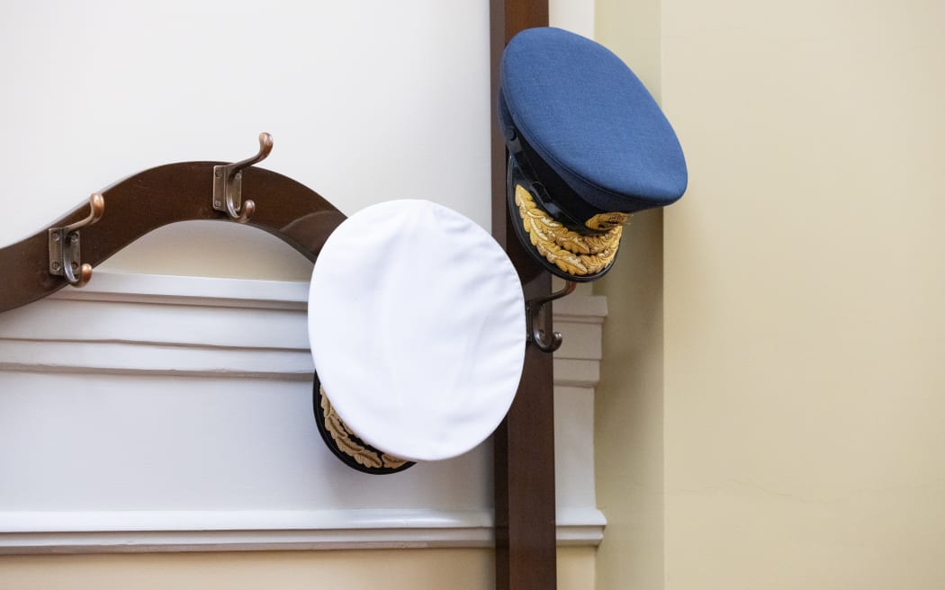 Uniform caps from Defence Force top brass wait outside a Parliamentary select committee.