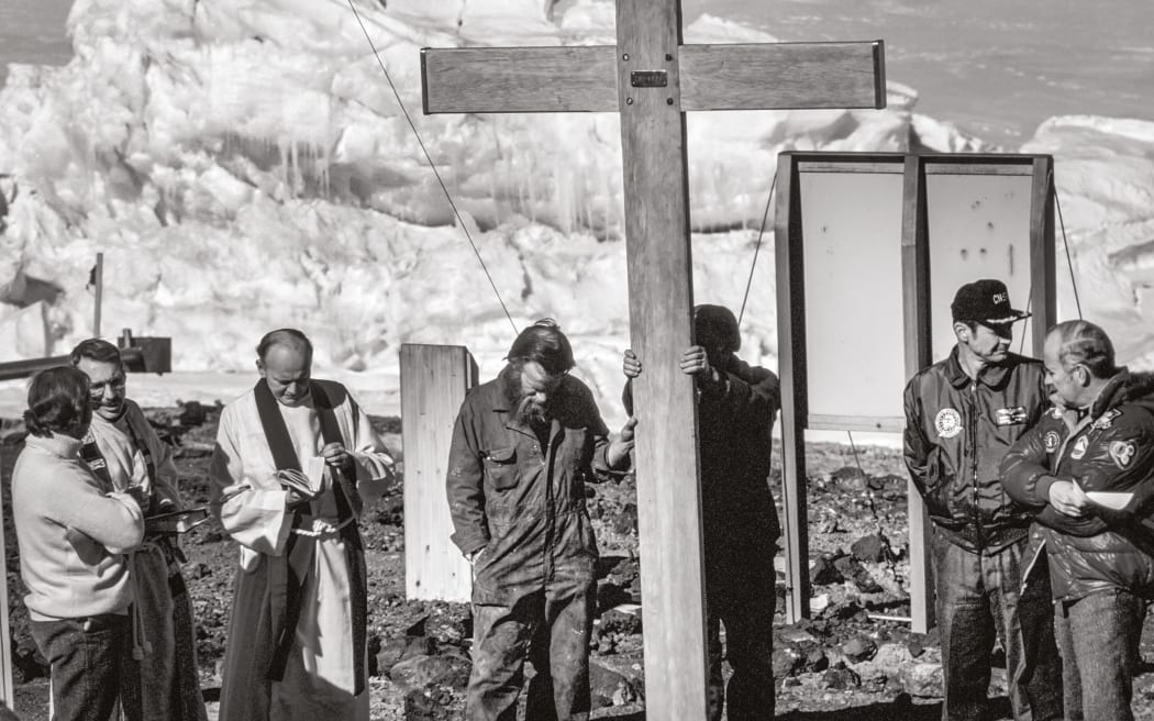 The dedication service of the crash memorial cross took place in front of Scott Base shortly after everyone had evacuated the crash site. From left: Mike Prebble, leader of Scott Base, talks to two US Navy chaplains; Garth Varcoe and Ted Robinson hold the cross; US Navy Commander Darryl Westbrook; and Bob Thomson, superintendent of DSIR Antarctic Division.