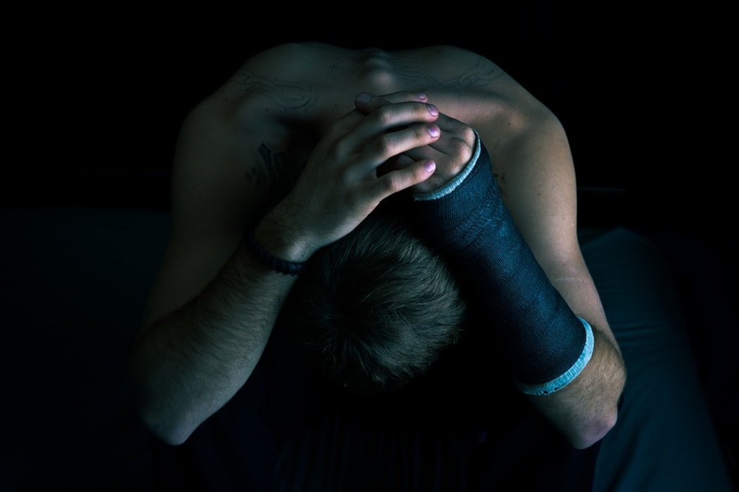 Man leaning forward with hands over his head.