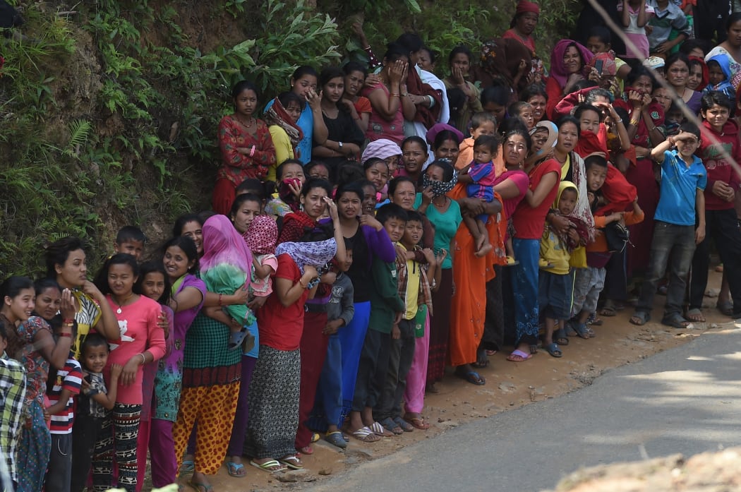 Nepalese people queue for relief aid from an Indian Air Force (IAF) helicopter team in northern-central Gorkha.